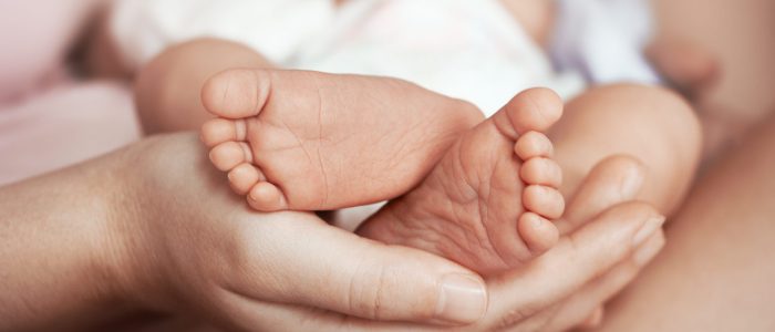 Feet of newborn baby on mother's palm